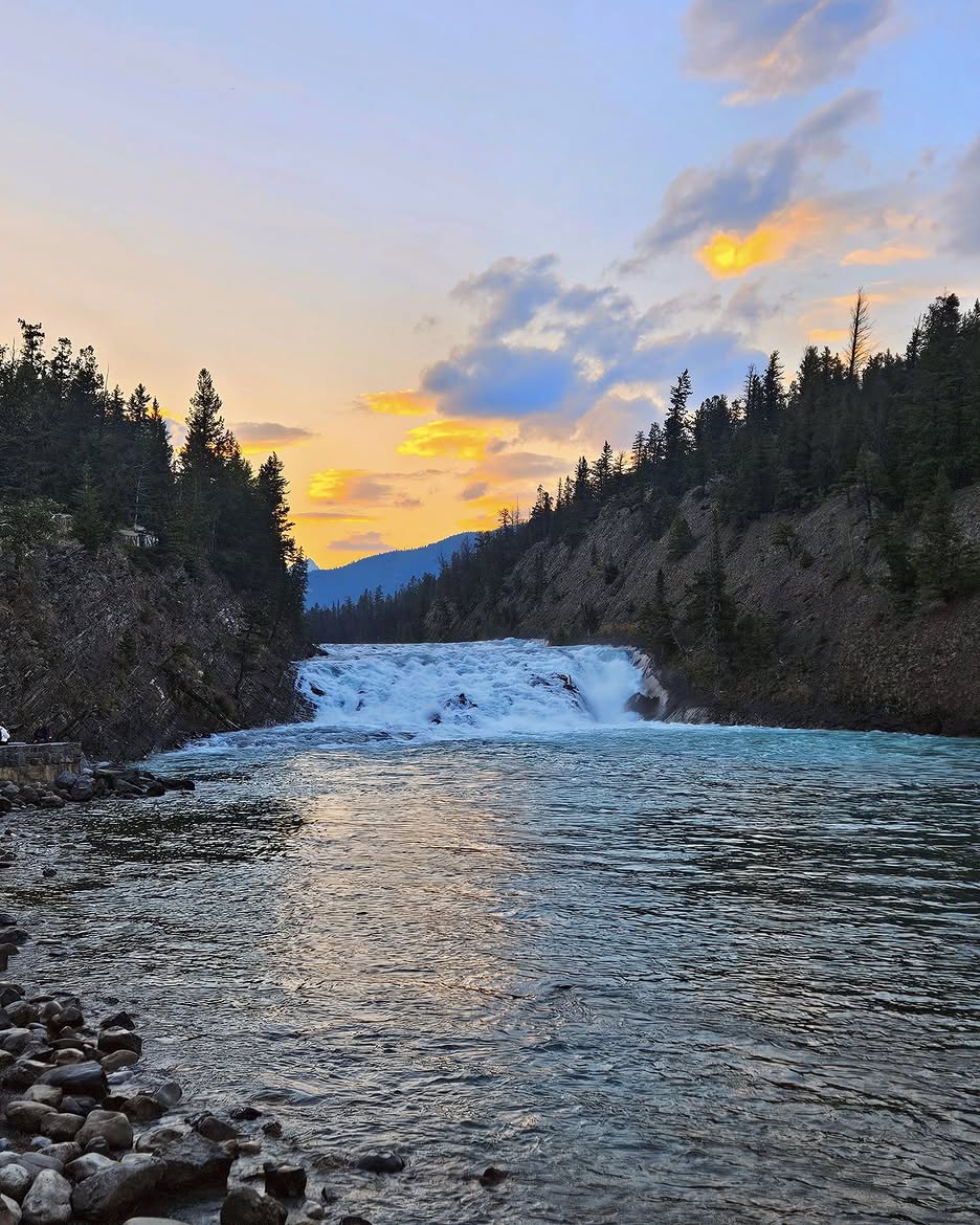 Bow Falls at sunset with golden light over the surrounding mountains